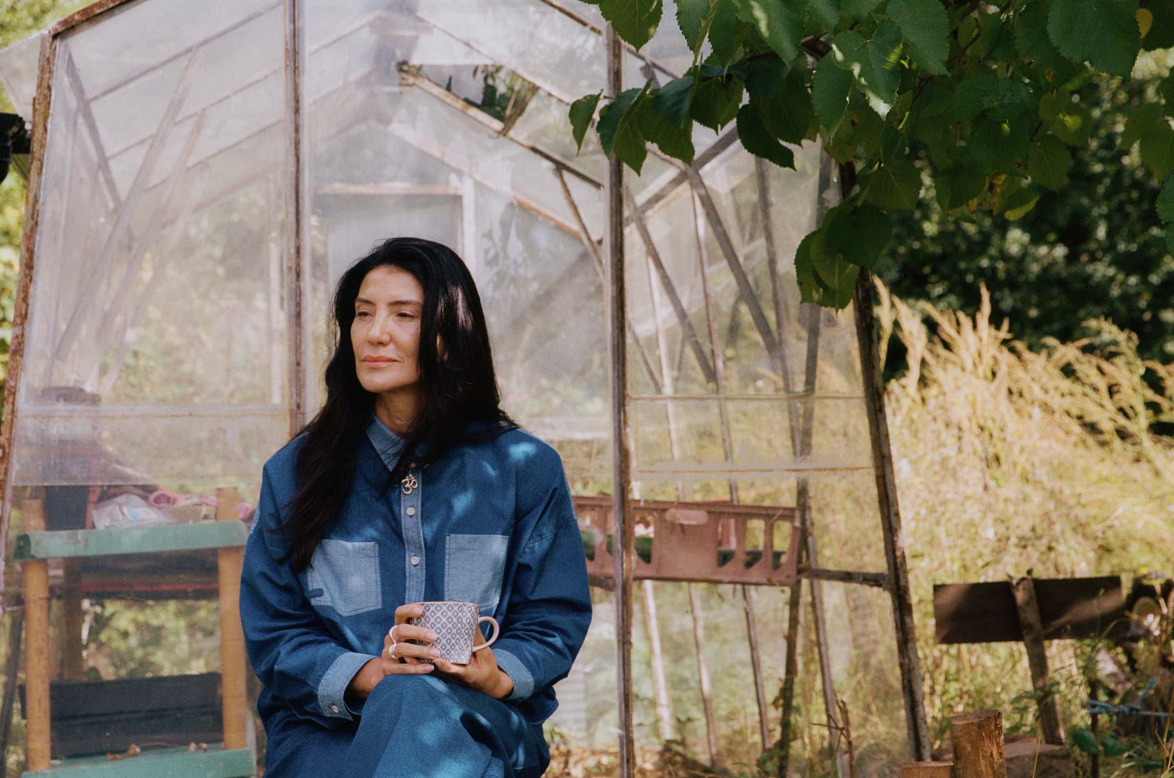 Lela Shirt in Japanese indigo denim, worn relaxed in a sunlit garden setting — made in the UK by Saywood