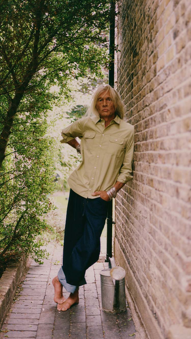 Eddy Utility Shirt in olive, styled with wide-leg indigo jeans against a brick wall — sustainable menswear made in England by Saywood