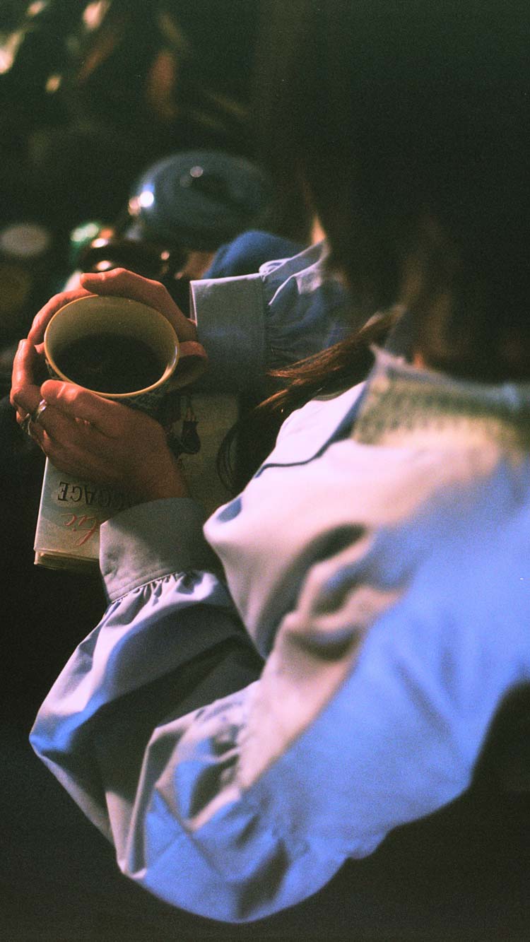 Edi Lace Collar Shirt in pale blue, worn relaxed with a cup of tea and a book — sustainable luxury womenswear made in England by Saywood