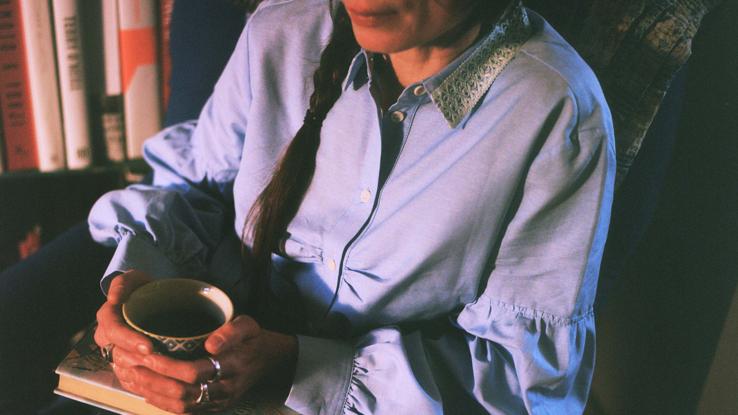 Edi Lace Collar Shirt in pale blue, worn relaxed with a cup of tea and a book — sustainable luxury womenswear made in England by Saywood