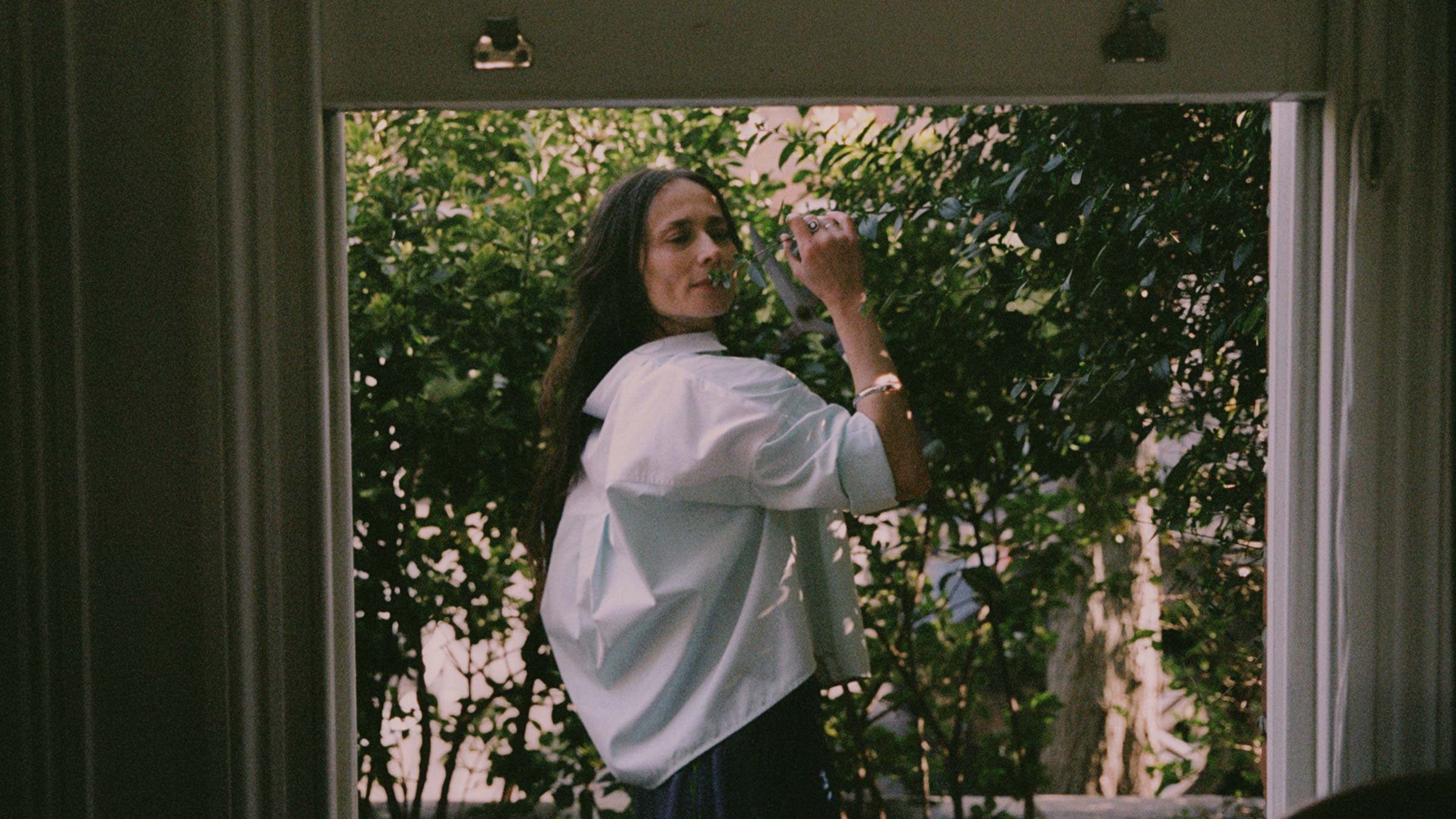 Lela Boxy Shirt in green and blue cotton colourblock, worn outdoors in dappled garden light — made in the UK by Saywood