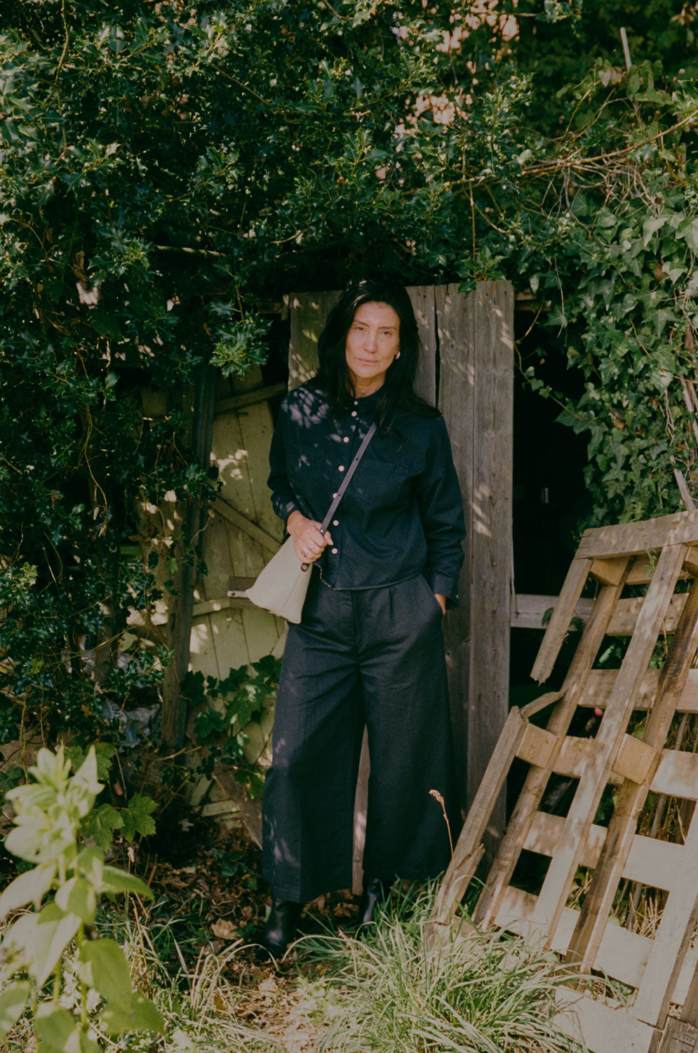 Lela black denim shirt styled with black Amelia wide leg trousers, outdoor lifestyle shot, by Saywood