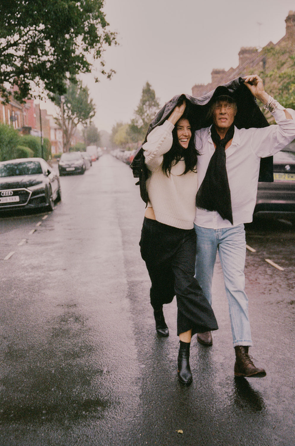 Adams cream fisherman's rib sweater side view, styled with black wide leg trousers, couple outdoor lifestyle shot