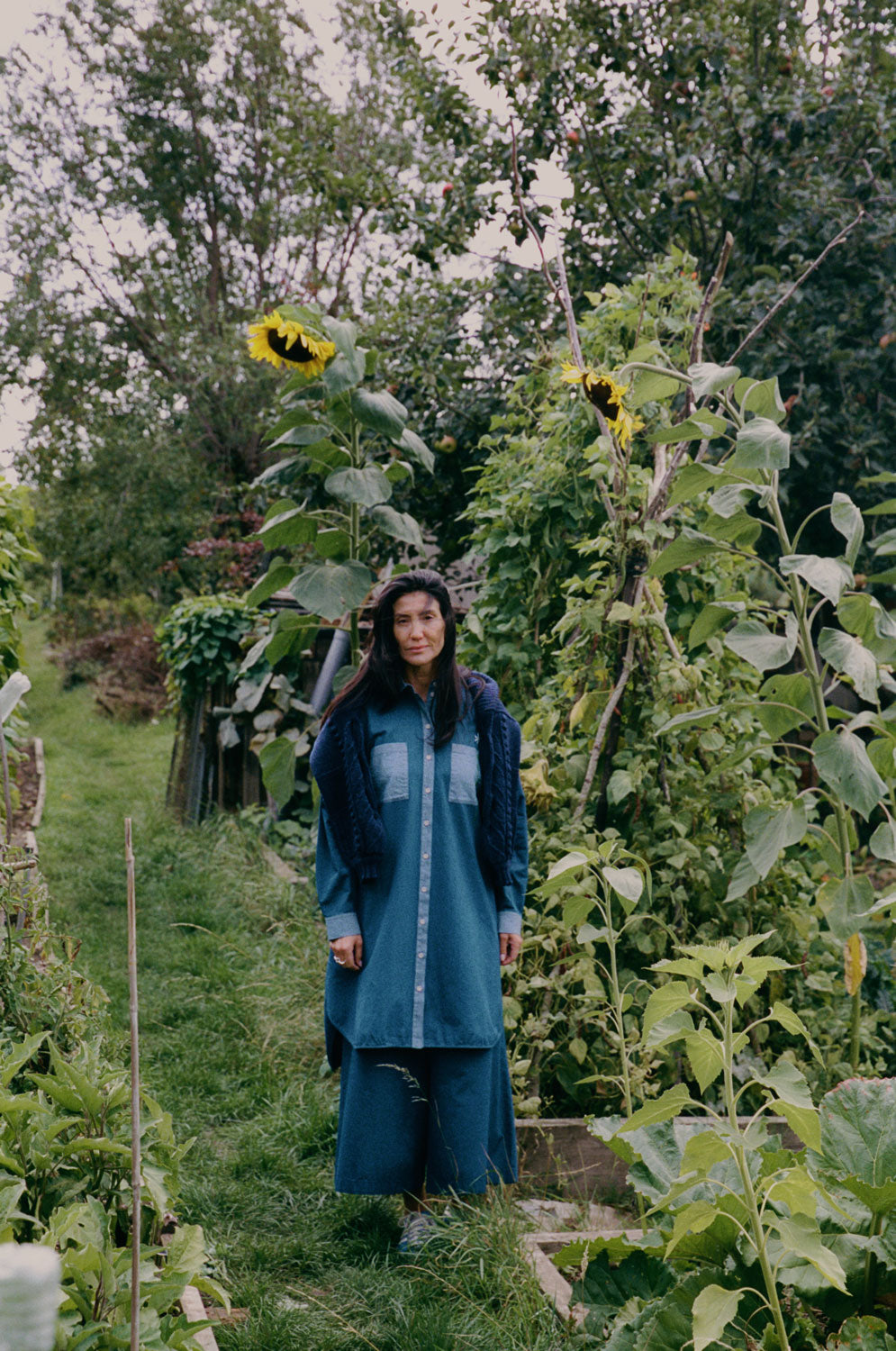 Frida navy cardigan layered over Japanese denim shirtdress in outdoor allotment setting, sustainable styling by Saywood