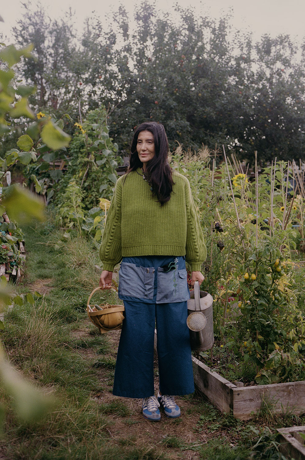 Adams moss green chunky knit sweater styled with Japanese denim trousers in allotment setting, handcrafted by Saywood