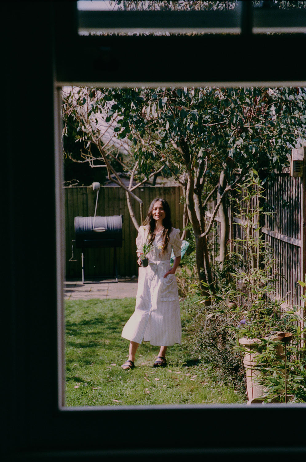 Lifestyle shot: Rosa white pinstripe shirtdress with detachable belt and ruffle pockets, made in London by Saywood